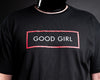 A close-up of slave D wearing a black short-sleeve t-shirt with a red rectangular outline and the words 'GOOD GIRL' printed in white across the chest.