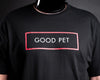 A close-up of a black crewneck t-shirt worn by slave D, featuring a graphic print on the chest with a red rectangular border and the words 'GOOD PET' in white.