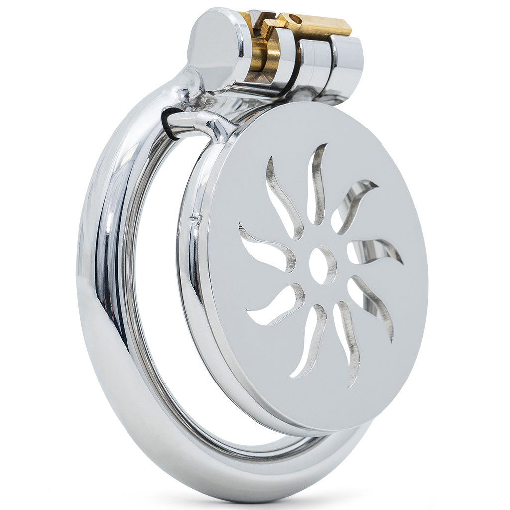 A polished steel chastity device featuring decorative cut outs and a small brass locking mechanism, shown on a plain white background.