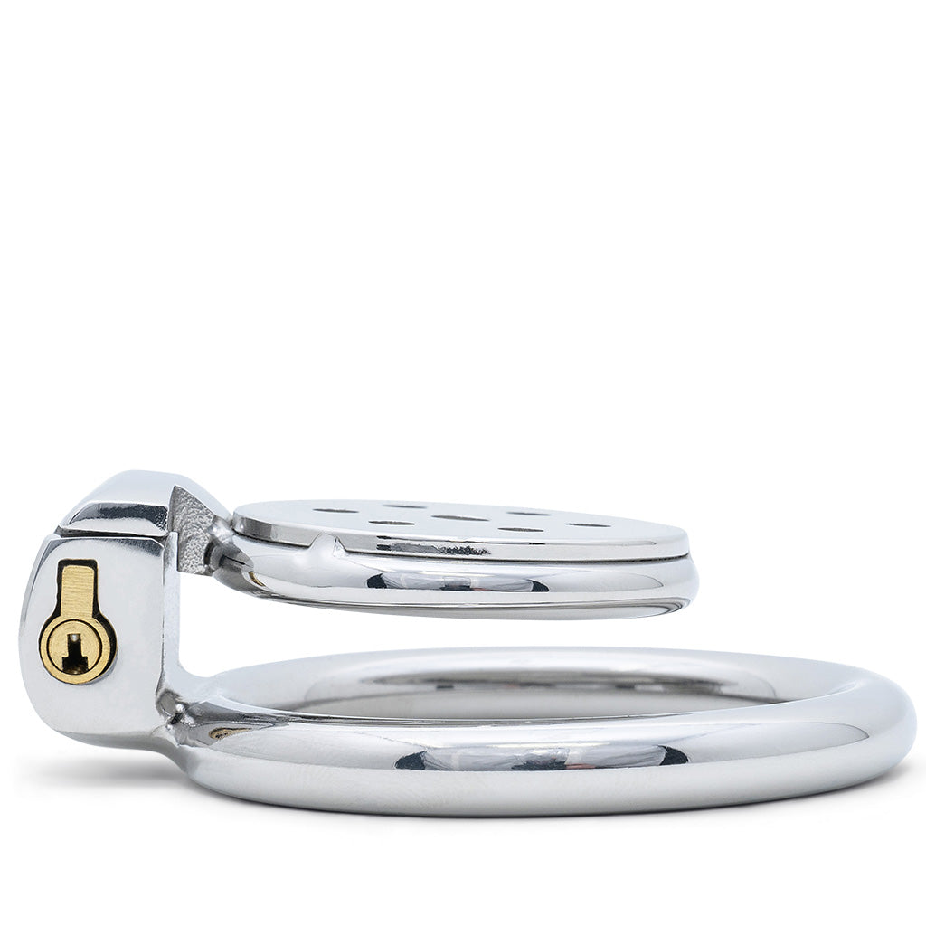 A polished silver chastity device with a lock mechanism featuring a brass keyhole, shown on a clean white background.