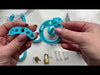 Assembling the blue kit with the back ring, bridge pieces, spacers and cage. A brass padlock is attached at the end.