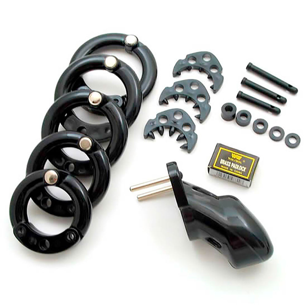 Black HoD300 male chastity device with all accessories laid out on a white table. It shows 5 back rings, 3 spiked ring attachments, 3 guide pins, 5 spacers, the black cage and a brass padlock box.